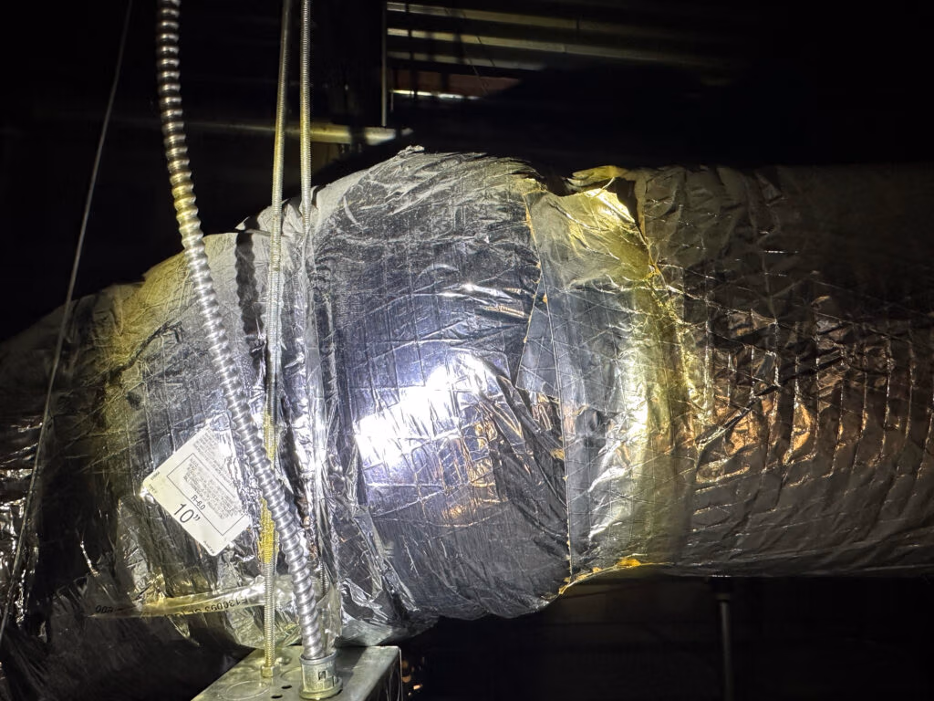 Close-up of improperly sealed HVAC ductwork with loose and uneven tape wrapping.