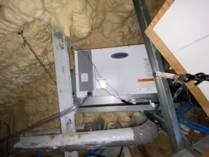 Dehumidifier unit installed in an attic space with foam insulation.