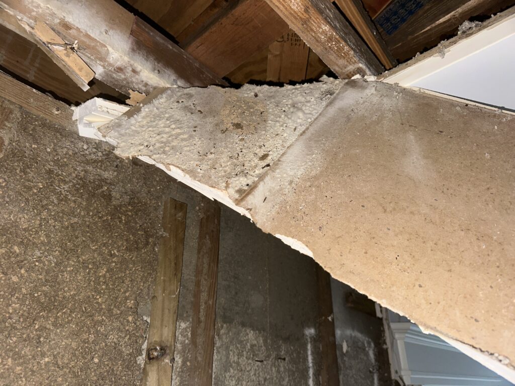 Ceiling panel with water and mold damage in a building structure.