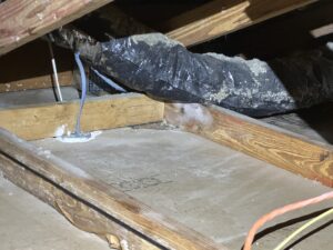 Attic space showing HVAC ductwork with insulation and visible condensation issues.