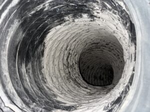 Inside view of an HVAC duct system showing layers of dust and mold on the interior surface.