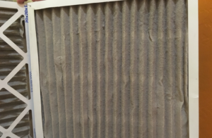 Close-up of a dirty HVAC air filter clogged with dust and debris.