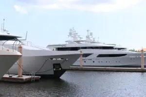 Luxury white yacht docked in palm beach marina under a clear blue sky.