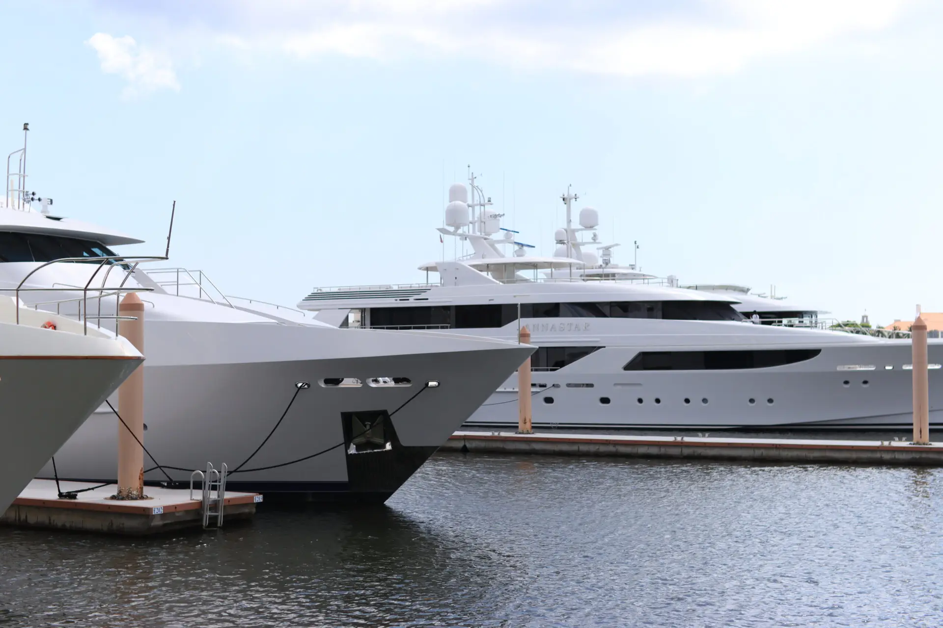 Luxury white yacht docked in palm beach marina under a clear blue sky.