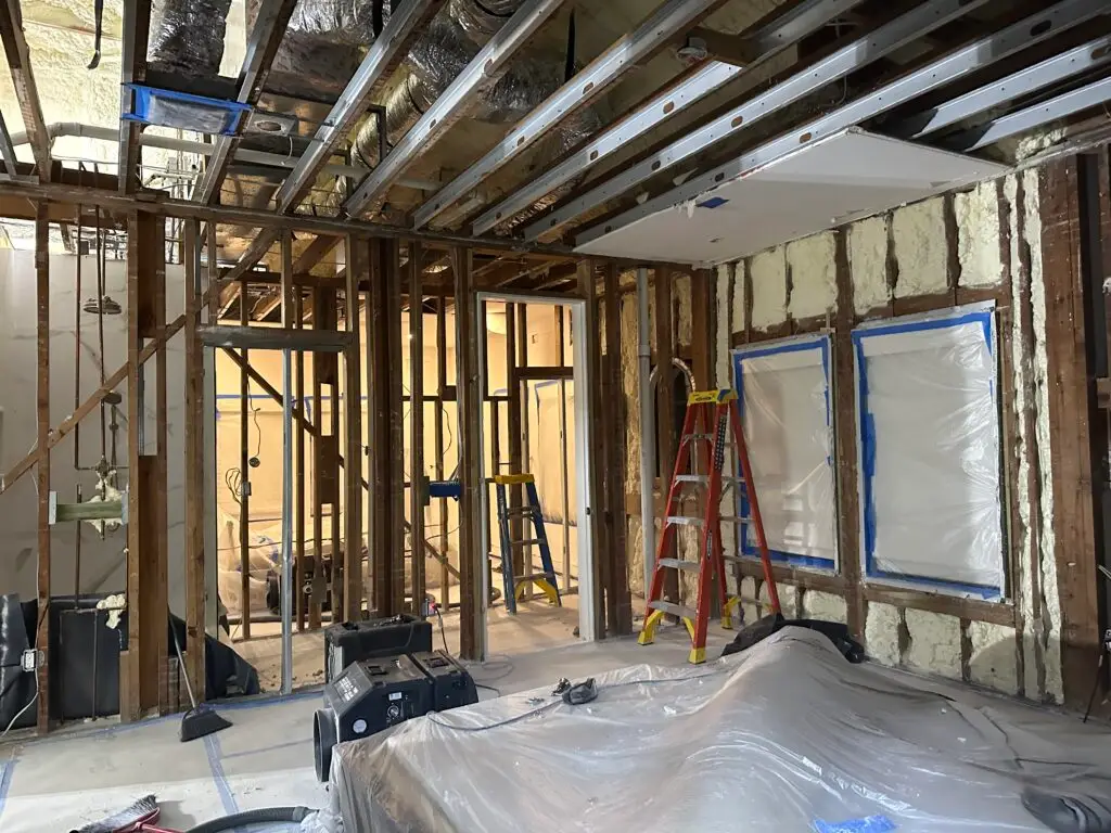 Residential mold remediation project with exposed framing, containment barriers, and HEPA air scrubbers in place.