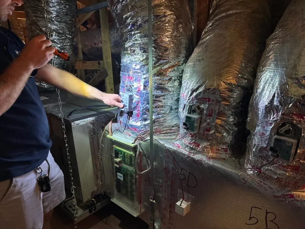 Technician inspecting a whole-home air quality system installation with integrated HVAC ductwork.