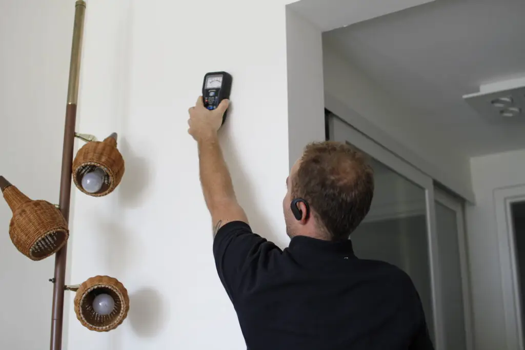 GreenFox technician using a moisture meter on a residential wall to detect moisture levels and assess potential water damage.