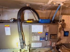 HVAC air handler enclosed in drywall inside a South Florida attic showing moisture damage and microbial growth caused by condensation