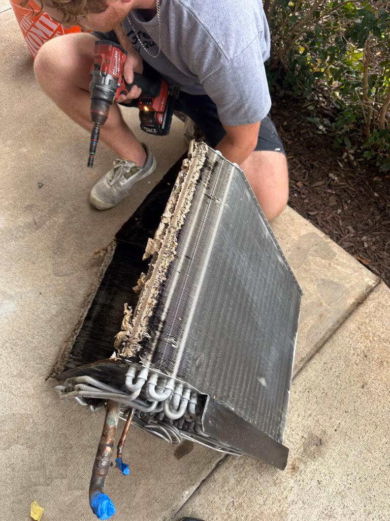 Removed HVAC evaporator coil with heavy dust and debris buildup, being serviced for thorough cleaning
