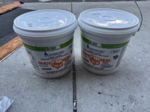 Two buckets of Hardcast Duct Seal 321 HVAC duct sealant placed on concrete surface for air sealing application