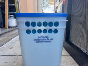 Water bucket placed against rear intake of Titan 4000 hydroxyl maximizer for humidity input