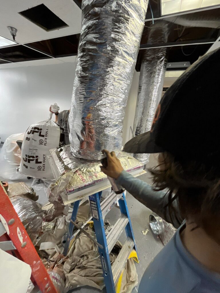 Technician fitting ductwork in place