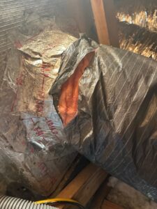 shows damaged and improperly sealed flexible HVAC ductwork in an attic.