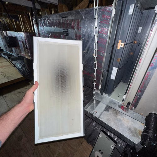 Technician holding a HEPA filter installed in an attic HVAC system for advanced air purification.